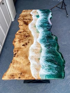 the table is made out of wood and has an ocean wave painted on it's surface