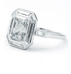 an emerald cut diamond ring on a white background