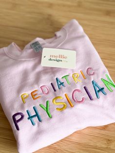 a t - shirt with the words pediatric physician on it sitting on a wooden surface