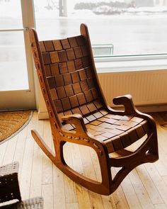 a wooden rocking chair sitting on top of a hard wood floor next to a window