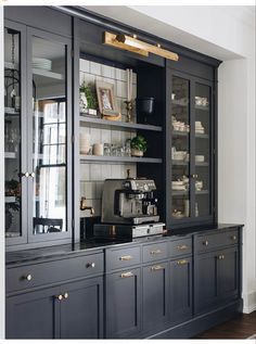 a black and gold china cabinet in a white walled dining room with wood floors, glass doors, and rug on the floor