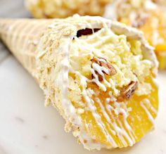 an ice cream cone filled with oranges and nuts on top of a white plate