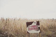 a sign that is in the middle of a field with some dry grass behind it