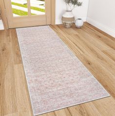 a white and pink rug sitting on top of a wooden floor next to a door