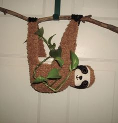 a stuffed panda bear hanging from a tree branch with leaves on it's back