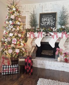 a decorated christmas tree in front of a fireplace with stockings on the mantels