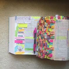 an open book with lots of different colored papers on it and writing in the pages