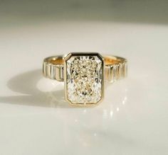 a yellow gold ring with a fancy diamond in the center, on a white surface