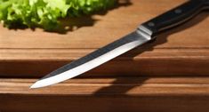 a knife sitting on top of a cutting board next to lettuce