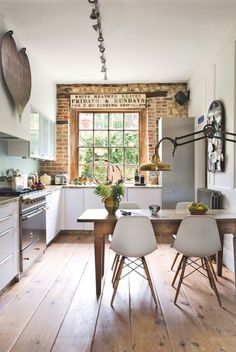 a kitchen with wooden floors and white walls, along with an island table surrounded by chairs