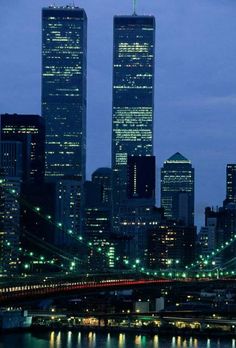 the city skyline is lit up at night, with skyscrapers in the foreground