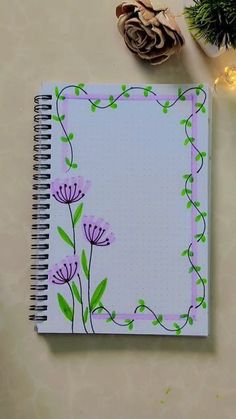 an open notebook with flowers on it next to a pine cone and some other items