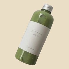 a bottle of green liquid with a white label on the top is shown in front of a beige background