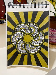 a yellow and black spiral design on a notepad next to a potted plant