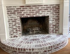 a brick fireplace in the middle of a living room with wood floors and white trim