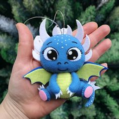 a hand holding a small blue dragon ornament