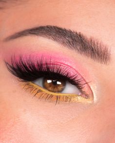 a woman's eye with bright pink and gold makeup on her eyeshadp