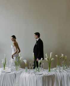 a man and woman standing next to each other in front of a table covered with white flowers