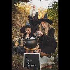 a woman and two children dressed up as witches sitting on the ground in front of a caulder