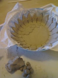 a white bowl sitting on top of a table next to some rocks and plastic wrap