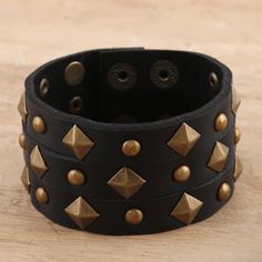 Covered in faceted studs, Indian artisan Deepika Lohani's eye-catching cuff is sure to add some edge to your outfit. Designed for both men and women, the cuff is hand crafted from wide strips of black leather and embellished with brass-plated iron studs. Two row of brass-plated iron snap buttons let you adjust the size to fit your wrist. Punk Cuff Bracelets With Rivets, Edgy Adjustable Cuff Leather Bracelet, Adjustable Bohemian Leather Bracelet For Party, Adjustable Metal Jewelry With Spikes, Adjustable Spiked Metal Jewelry, Adjustable Punk Jewelry With Spikes, Black Bracelets With Rivets As Gift, Adjustable Edgy Jewelry With Spikes, Adjustable Spiked Punk Jewelry