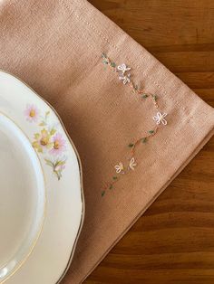 a white plate with flowers on it sitting next to a pink placemat and napkin