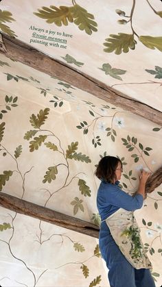 a woman is painting the ceiling with floral designs on it and she's holding a brush