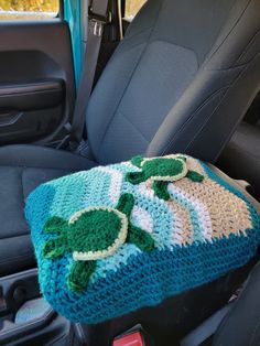 a crocheted turtle blanket sitting in the back seat of a car