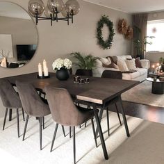 a dining room table and chairs in front of a large mirror with candles on it