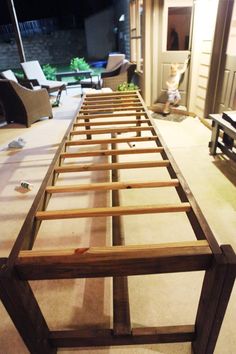 a wooden bed frame sitting on top of a floor next to a chair and table