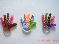 three different colored beads in small vases on a white surface with one beaded and the other made out of plastic beads