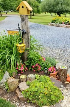 a birdhouse is sitting on top of a tree stump in the middle of a garden