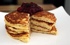 a stack of pancakes on a white plate topped with cranberry compote