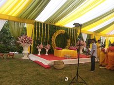 an outdoor wedding setup with flowers and decorations on the stage, surrounded by yellow draping