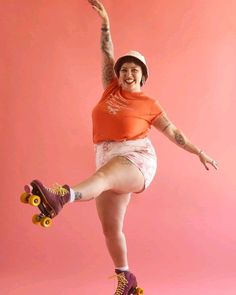 a woman in an orange shirt and white skirt is doing a trick on a skateboard