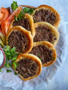 small sandwiches with meat and veggies are on a plate next to a bowl of ranch dressing