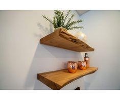 two wooden shelves with vases and candles on them in a corner next to a wall