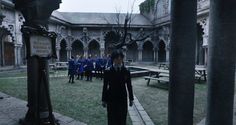 a group of people standing in an old building with trees and benches on the ground