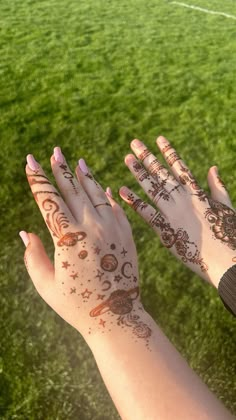 two hands with henna tattoos on them are in front of a soccer ball field