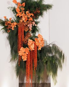 an arrangement of orange flowers and greenery hanging from a fireplace mantel in a living room