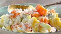 a close up of a bowl of fruit salad with a spoon on the side,