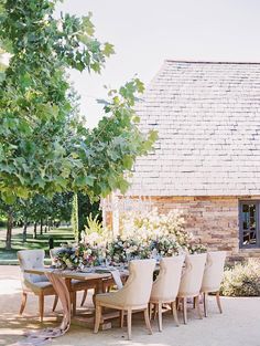 an outdoor dining table with chairs and flowers on it