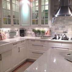 a kitchen with white cabinets and marble counter tops