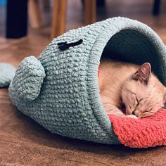 a cat sleeping in a crocheted fish bed