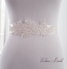 "This vintage inspired bridal sash is embellished with delicate floral lace for an elegant finish to your bridal attire. The sash is made with double faced Ivory satin ribbon 1.5\" wide and is 3 yards long. Beautiful addition to your wedding gown. PROCESSING: Please allow 3-5 business days for production. Also be sure to leave the date you require your order or your wedding date. For rush order, please convo us before placing your order. SHIPPING: Order will be shipped via USPS First Class Mail Lace Bridal Belt With Sashes For Wedding, Lace Bridal Belt For Ceremony, White Lace Bridal Belt For Ceremony, White Lace Wedding Sash, Lace Bridal Belt With Lace Trim For Wedding, Cream Bridal Belt With Sashes For Wedding, White Bridal Accessories With Sashes, White Embroidered Bridal Belt For Wedding, White Fitted Bride Sash