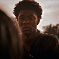 a close up of a person talking to another person with trees in the back ground