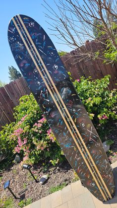 two surfboards are standing in the middle of a flowered garden and one is upside down