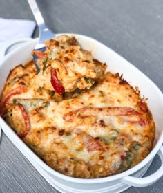 a white casserole dish filled with cheesy bread and vegetables on a table