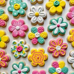 decorated cookies are displayed on a white surface with pink, yellow and blue flowers in the middle