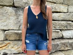 a woman standing in front of a stone wall with her hands on her hips and looking at the camera